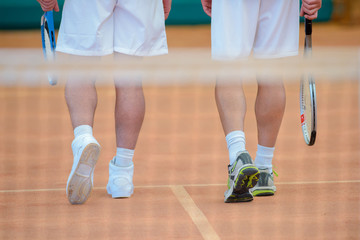 View of two men's legs on tennis court