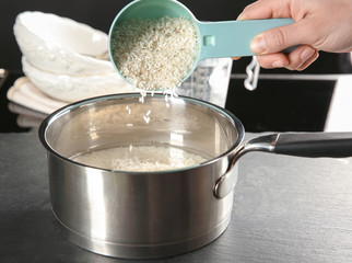 Woman filling saucepan with rice