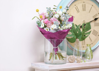 Beautiful composition with fresh flowers and vintage clock on mantelpiece