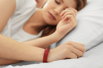 Fototapeta na wymiar Young woman with sleep tracker resting in bed at home, closeup