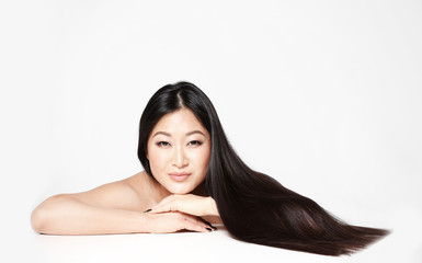Beautiful Asian woman with long straight hair on light background