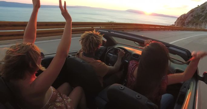 Handsome black man partying with friends while driving in convertible at sunset