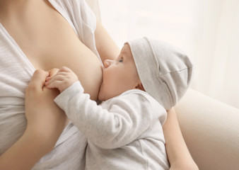 Young woman breastfeeding her little baby at home, closeup - obrazy, fototapety, plakaty