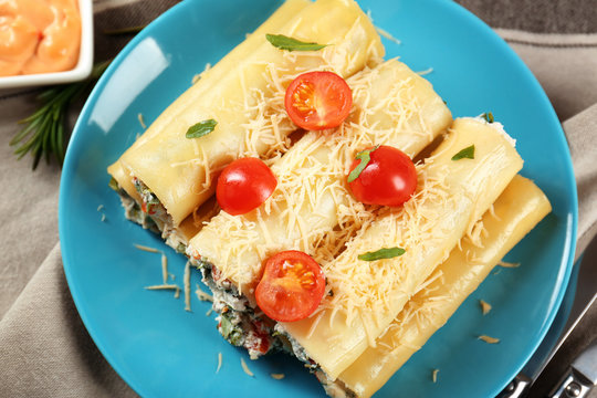 Delicious stuffed cannelloni with cherry tomatoes on blue plate