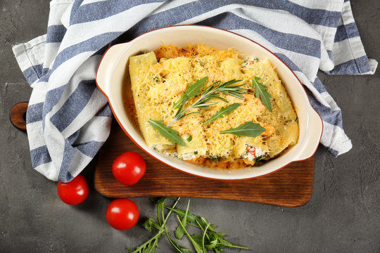 Delicious stuffed cannelloni in baking dish on table