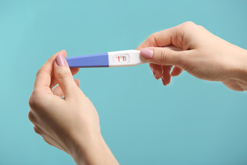 Pregnancy test in hands on color background
