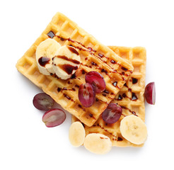 Tasty waffles with delicious fruits and syrup on white background