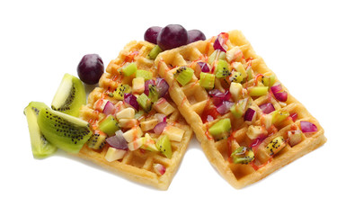 Tasty waffles with delicious fruits and syrup on white background
