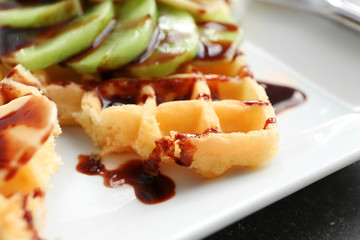 Tasty waffles with delicious fruits and syrup on white plate, close up