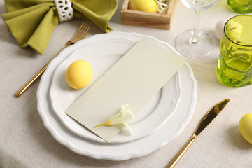 Beautiful Easter table setting with empty card on tablecloth