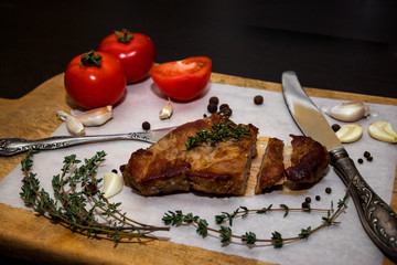 Juicy beef steak on a wooden old cutting board with spices and vegetables. On a black background for text design for restaurant menus. Food background.