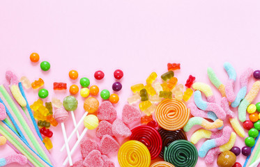 Bunte Bonbons und Fruchtgelee-Jujube auf rosa Hintergrund