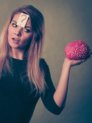 Woman thinking and holding fake brain