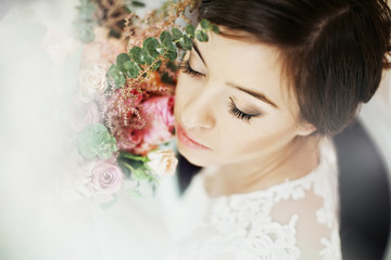 Beautiful bride in a lace dress with a bouquet of roses