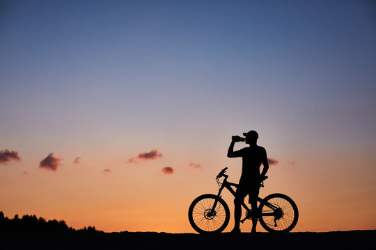 Attractive, healthy couple drink from their water bottles on mountain bikes. active outdoor lifestyle concept