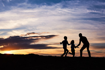 Fototapeta premium Father and children on the beach at the sunset time. Concept of friendly family.