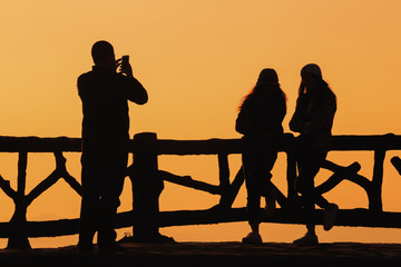 Naklejka na ściany i meble Silhouette people on background red sunset 