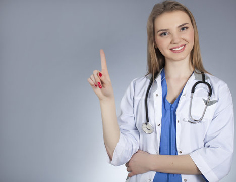 Young  attractive woman doctor holds  index  finger up and smile. 