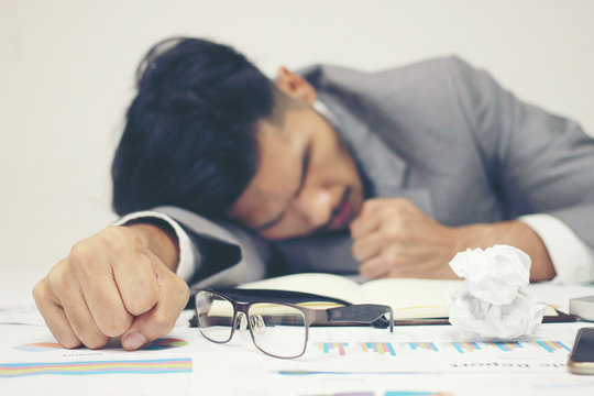 Businessman sleeping at his desk working over a laptop on background after he work all day all night, Tried overworked, Keep fighting in business concept.