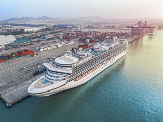 Naklejka premium passenger ship cruise is alongside berthed the terminal in port for transit the tourist in port congestion of berth in sunrise in background, in aerial view