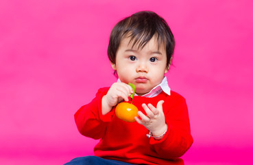 Asian boy holding a Mandarin orange