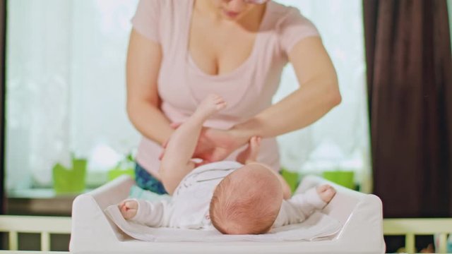 Mom changes the diaper of a small baby girl