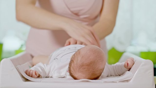 Mom changes the diaper of a small baby girl
