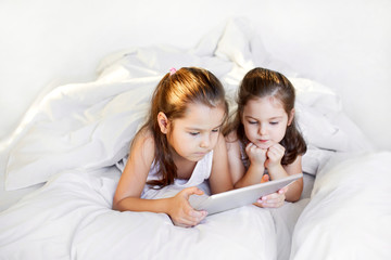 children play in the tablet in bed