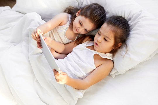 children play in the tablet in bed