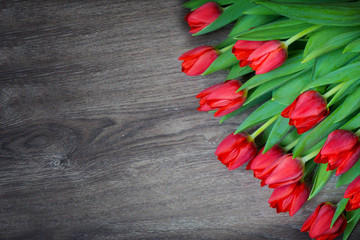 Red tulips on wooden background with space for text