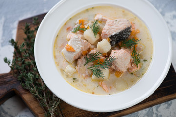 Close-up of salmon fish soup served in a white glass plate, studio shot