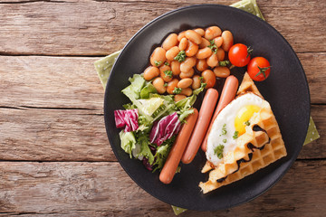 Savory breakfast: waffles with egg, sausages, beans and fresh salad close-up. Horizontal top view