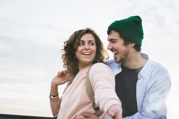 Obraz premium Man and woman look at each other and taking selfie with selfie stick on outdoors
