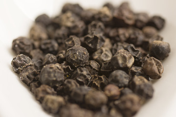 black pepper in white spoon on wooden background