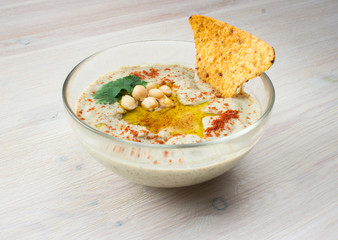 A bowl of creamy hummus with olive oil and chips.