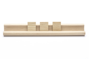 Three blank scrabble tiles on a wooden rack, on white background