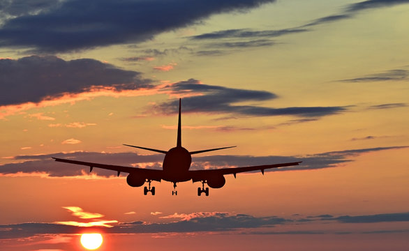 Silhouette of landing airplane at dawn