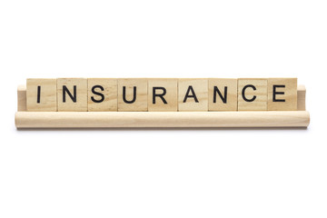 Word ''insurance'' on scrabble wooden letters on a rack, isolated on white background.