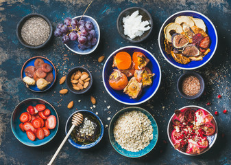 Ingredients for healthy breakfast over dark blue background, top view. Fresh and dried fruit, chia seeds, oatmeal, nuts, honey. Clean eating, vegan, vegetarian, healthy food, detox and dieting concept