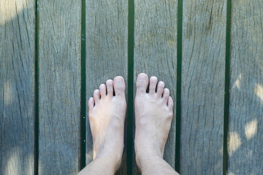 Feet on wooden pier over the blue water of the sea