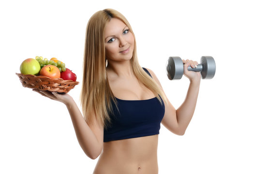 Beautiful blonde girl holding an apple and a dumbbell