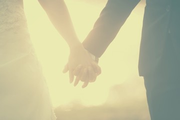 Love - romantic couple holding hands, beach sunset. Lovers or newlywed married young couple in romance on beautiful sunset at beach. Young woman and man in love walking hand in hand, Filtered Images
