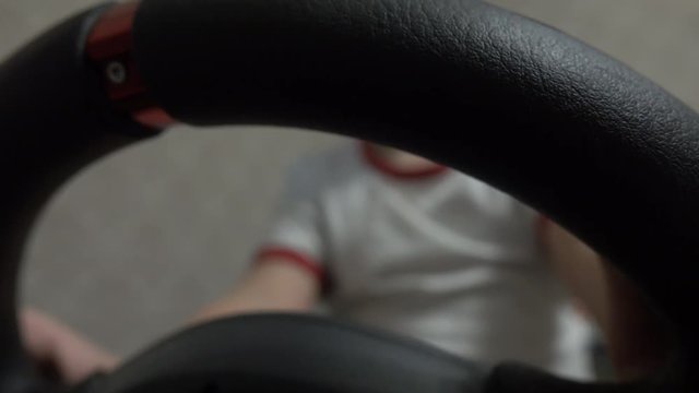 Little boy playing racing computer game using steering wheel. Newbee or beginner concept, 4K video