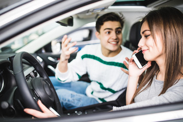 Side portrait of couple in car. Man with scream and gesture while girl talking at phone in car