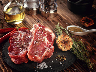 Raw pork neck steak on a stone plate.