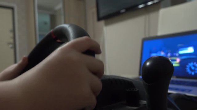 Little boy playing racing computer game using steering wheel. Newbee or beginner concept, 4K shot