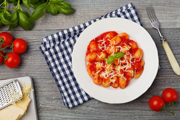 Serving gnocchi in tomato sauce with cheese. - obrazy, fototapety, plakaty