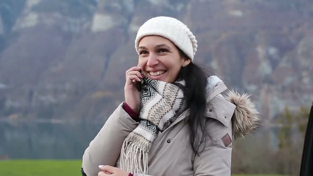 Young beautiful woman talking by mobile phone on the background of the Alps.