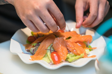 Obraz na płótnie Canvas Man's hands make salad. Salad with pieces of fish. Recipe of salad with salmon.