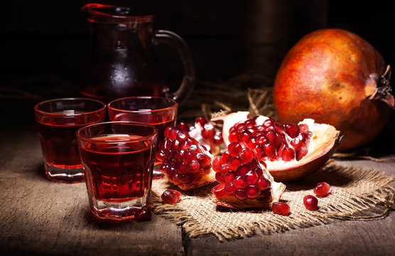 Homemade pomegranate liqueur, still life in rustic style, vintage wooden background, selective focus